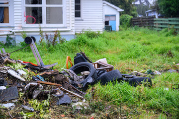 Rubbish piled up in the front yard of an abandoned residential house in the rain. House is ready...