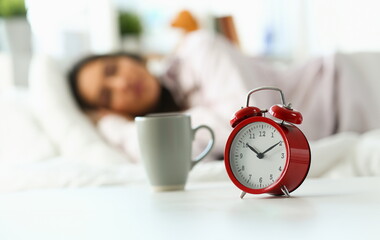 Beautiful indian woman peacefully lying in bed sleeping early morning while alarm clock going to...
