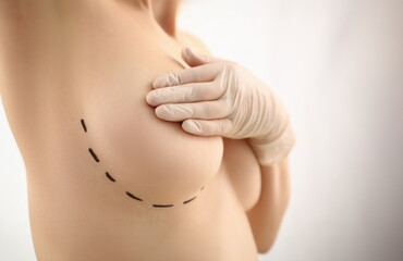 Female hand in gloves holding breast closeup on doctor mammology clinic reception. Mammary glands...