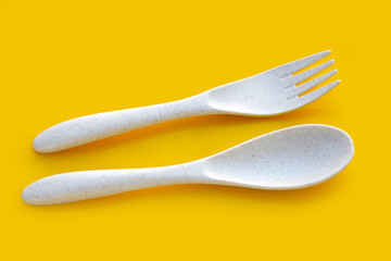 Spoon and fork on yellow background.