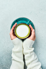 cup of delicious matcha latte in female hands on light gray background, closeup. Top view.