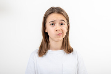 A teenage girl grimaces with displeasure on a white background, isolated.