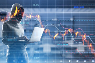 Hooded figure using laptop with stock market decline graphs