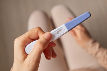 Childbearing maternity. Unrecognizable woman hand holding pregnancy test with two stripes positive result future mother waiting for childbirth.