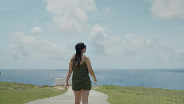 Girl walking to the end of the cliff and looking out to the sea