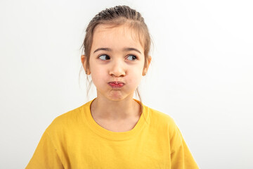 Little Caucasian girl makes funny faces on a white background isolated.