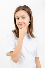 Fototapeta premium A schoolgirl thoughtfully holds her hand near her face on a white background.