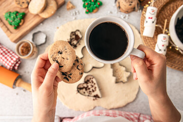 Homemade cookies and cup of coffee in female hands, Christmas baking, top view.