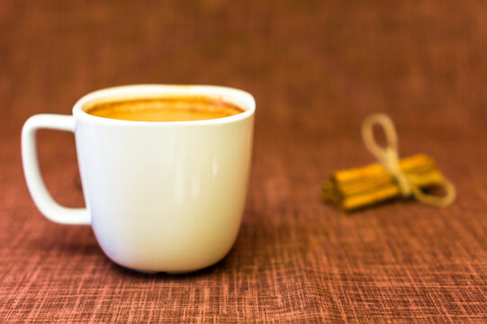 Cup of hot coffee nad cinnamon on a brown background/ Image with copyspace