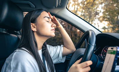 Tired young woman car driver suffering from headache migraine driving vehicle.