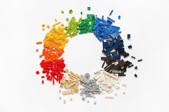 Pile of many various colorful rainbow colored stackable plastic toy bricks in circle shape on white background. Copy space. Top view. Lego blocks. Novosibirsk, Russia - October 26, 2023.