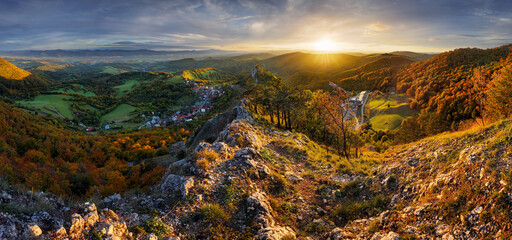 Mountains at sunset in Slovakia - Vrsatec. Landscape with mountain hills orange trees and grass in fall, colorful sky with golden sunbeams. Panorama