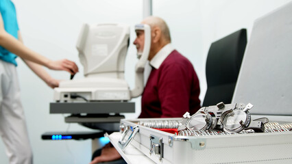An elderly man undergoes an eye examination in a modern clinic. An expert checks vision using diagnostic ophthalmological equipment. - obrazy, fototapety, plakaty