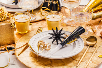New Years Eve celebration. Holidays served table with champagne and and luxury golden cutlery, with...