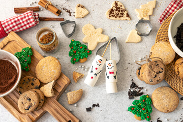 Marshmallow snowmen and homemade cookies on the kitchen table, top view.