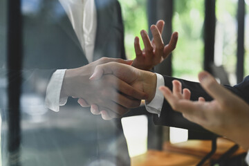 Businesspeople shaking hands after closing deal or successful negotiations at meeting