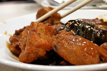 People eating honey glazed barbecued pork appetizers on table inside Chinese restaurant