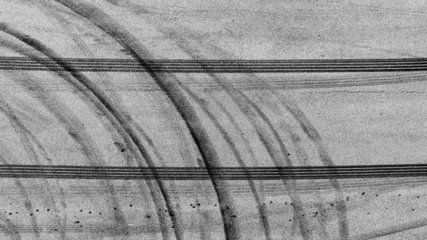 Zelfklevend Fotobehang Aerial view tire track mark on asphalt tarmac road race track texture and background, Abstract background black tire track skid on asphalt road, Tire mark skid mark on asphalt road. © Kalyakan