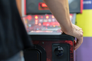 Detail of hand on the control button of a pinball. Defocused background