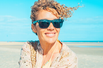 Summer portrait of cheerful happy adult young woman with sunglasses admiring the beach. Holiday vacation lifestyle with pretty female people tourist enjoying and relaxing in leisure outdoor