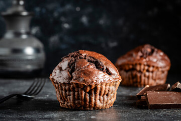 Chocolate muffin on dark background, closeup. Homemade delicious chocolate muffins on black board