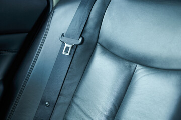Detail of a black leather seat belt in a modern car.