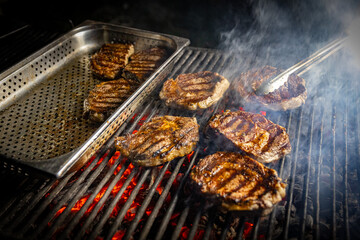 Rib-eye steaks cooking on flaming grill.