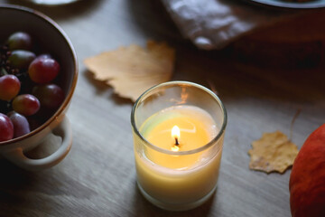 Cup of tea or coffee, plate with desserts, dried oranges, bowl of grapes, scented candles, vintage books, pumpkins and autumn leaves on the table. Autumnal hygge. Selective focus.