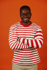 Handsome african american man posing with arms crossed isolated on orange background
