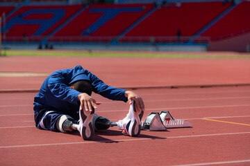 Disabled athletic man stretching and warming up before running on stadium track - obrazy, fototapety, plakaty