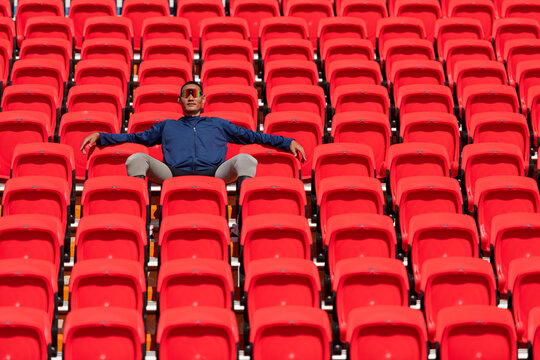 Disabled athletes in a blue shirt sitting on the red seats at the stadium, Prepare for running training.