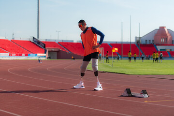 Obraz premium Disabled athletic man stretching and warming up before running on stadium track