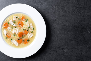 Chicken soup with vegetables on black background. Top view. Copy space