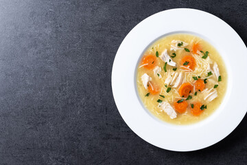 Chicken soup with vegetables on black background. Top view. Copy space