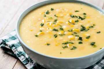 Corn soup in green bowl on wooden table. Close up