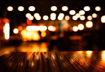 Bottom aligned wooden table in bokeh orange city illumination