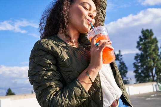 woman enjoys pink lemonade outdoors taking sip side view