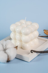 Fototapeta na wymiar A natural soy candle in the form of the bubble and vanilla and white cotton on a concrete tray