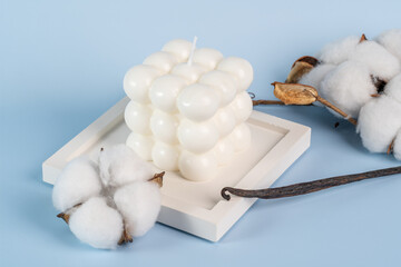 A natural soy candle in the form of the bubble and vanilla and white cotton on a concrete tray