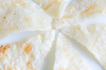 Close up six triangular roti dough on white dish.