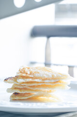 Six triangular roti dough stacked on white dish.
