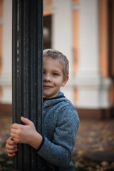 portrait of the little boy hugged the lamppost. autumn on a city street
