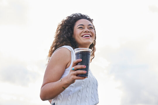 woman enjoying soft drink outdoors smiling looking past camera