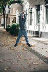 Fototapeta na wymiar photo of a boy in a high jump on the streets of an autumn city. wearing a blue jacket and blue jeans