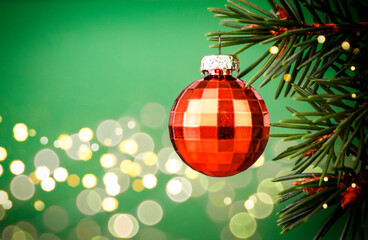 Christmas Fir tree with Golden Bauble and defocused lights in the green background. Copy Space