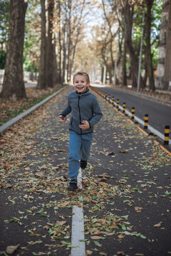 a boy runs along a stationary bike path in an autumn city. runs forward. street photo