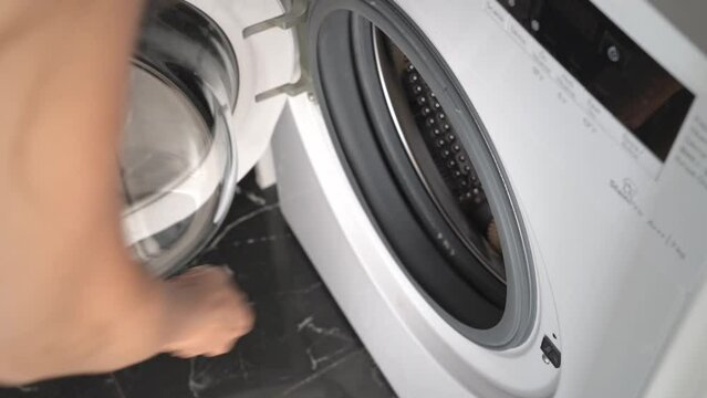 Washing dirty sneakers in washing machine, shoe care, women's hands close-up.