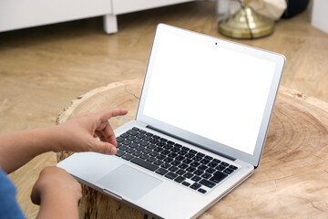 An individual engrossed in work on a white screen laptop. The laptop is perched on a richly grained...