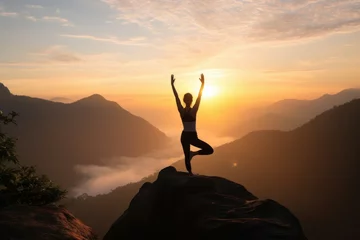  Silhouette of woman practicing yoga on mountain at sunrise © GVS