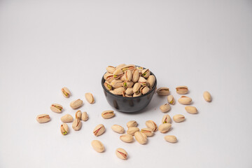 Pistachios or salt Pista on white bowl with white background, Pistachios or salt Pista scattered on the white background in a black bowl or wooden bowl. A raw salted pistachios consumed for food